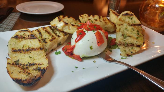 housemade burrata accompanied by roasted red peppers, pesto, and grilled crostini at Fireside Grille in Wichita