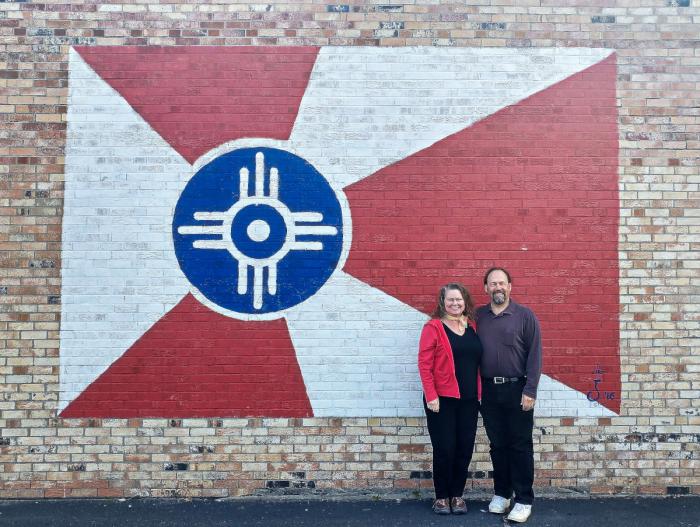 Jim and Theresa in front of the Doo-Dah Diner mural of the Kansas flag