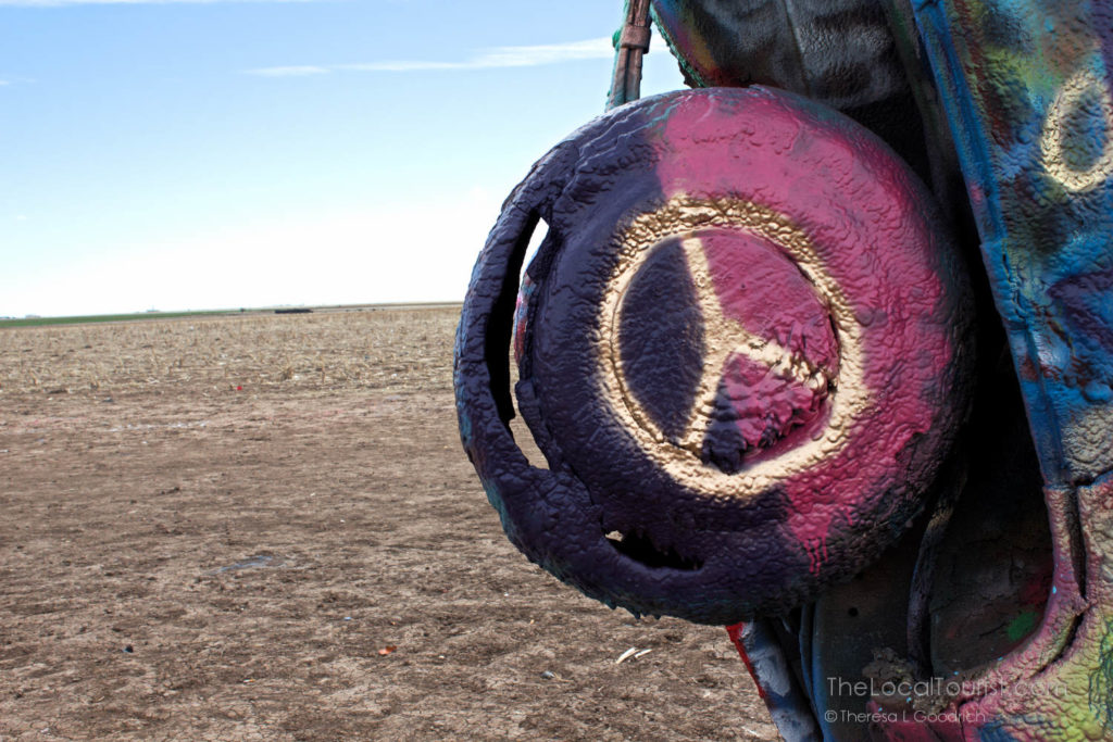 Peace symbol painted in gold on tire of buried Cadillac