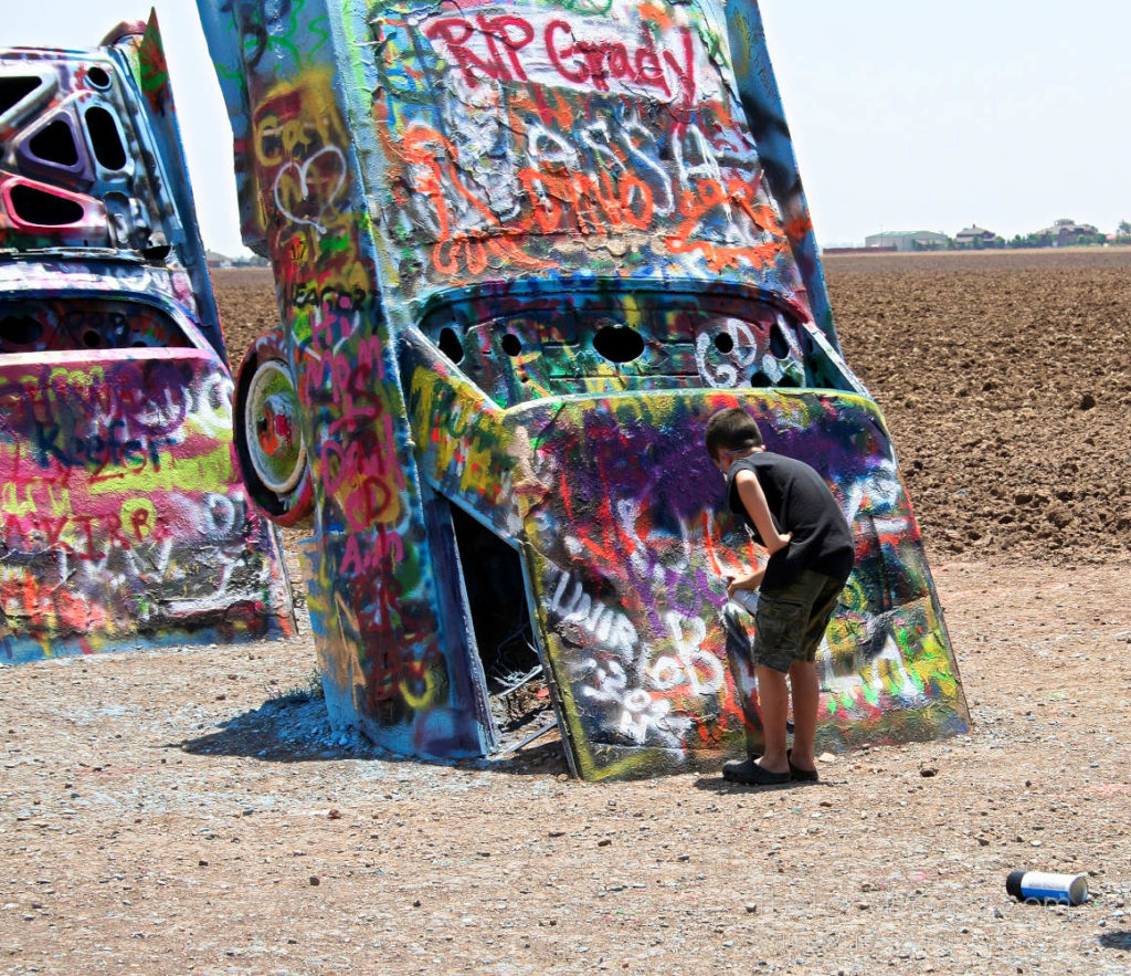 Boy spray painting at Cadillac Ranch