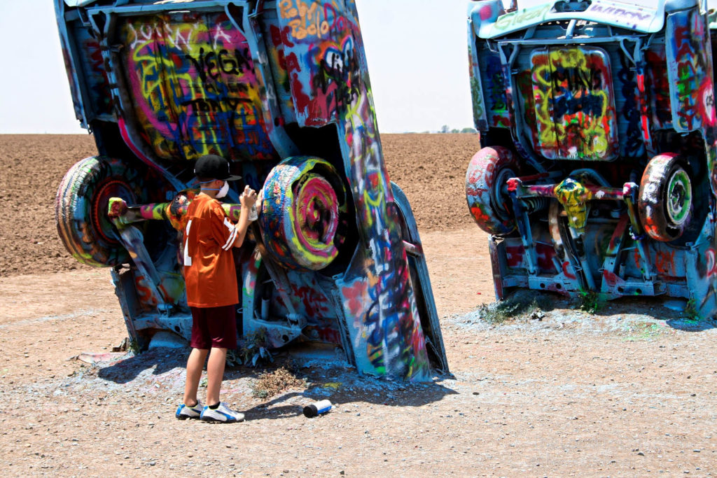 Boy spray painting at Cadillac Ranch