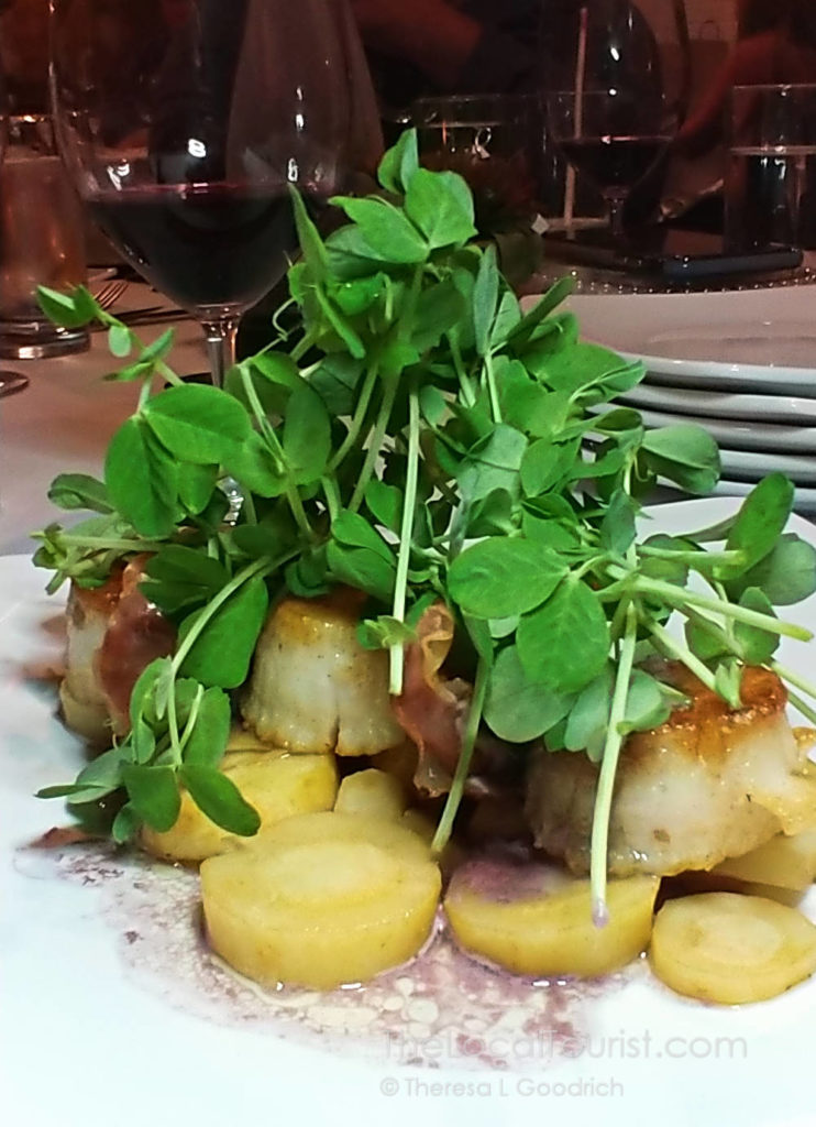Scallops served over root vegetables with a red wine garlic sauce, prosciutto, and topped with pea tendrils at 1776 Restaurant Crystal Lake